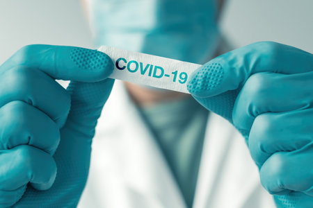Medical professional white plaster patch with Covid-19 label to apply to patient after vaccination, selective focusの写真素材
