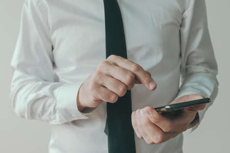 Businessman in white shirt typing text message on mobile smart phone, selective focus