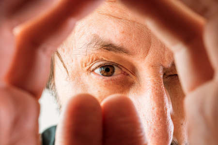 Man peeking through cupped hands, selective focusの写真素材