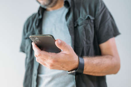 Casual man using smart mobile phone for communication, selective focus