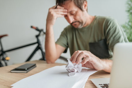 Telecommuter with creative block in home office crumpling sheet of paper, selective focusの写真素材