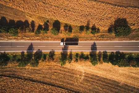 Top view aerial photo of truck on the road through plain landscape countryside in summer afternoonの写真素材