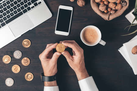 Cryptocurrency trading mobile phone app mockup screen, top view of male hands with smartphone and coinsの写真素材
