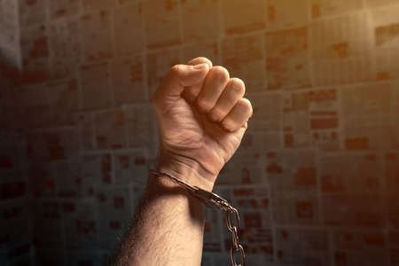 Handcuffed arrested journalist protesting with raised fist, conceptual imageの写真素材