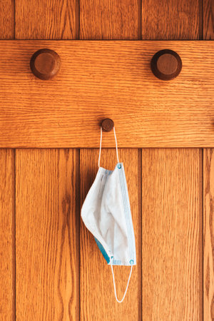 Protective surgical face mask on anteroom coat hanger stand during covid-19 pandemicsの写真素材