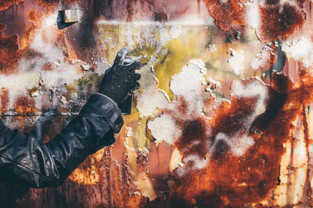Homeless man spray painting old train wagon with aerosol can. Unrecognizable male person hand close up in conceptual image with selective focus.の写真素材