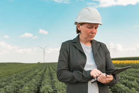 Female engineer with tablet computer on modern wind turbine farm during maintenance project planningの写真素材