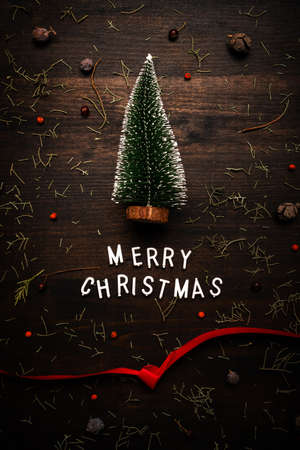 Merry Christmas text and fir tree top view flat lay on dark wooden backgroundの写真素材