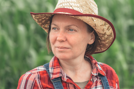 Portrait of female farmer standing in corn field, woman farm worker in maize plantationの写真素材