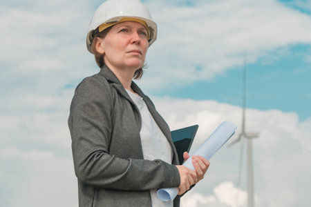 Portrait of female engineer on modern wind turbine farm during maintenance project planning