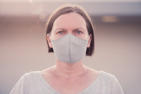 New normal, portrait of casual adult female person with protective face mask standing alone out on the streetの写真素材