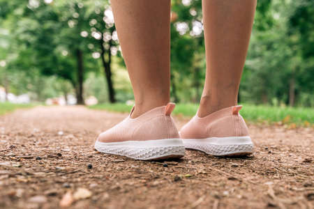 Female jogger preparing for running down the path in park, close up of legs and shoes with selective...