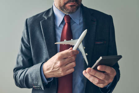 Businessman booking airplane flight ticket online using mobile phone application, conceptual image, selective focusの写真素材