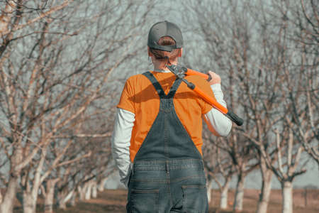 Female farmer posing with telescopic ratchet bypass lopper in walnut orchard ready for pruning on...