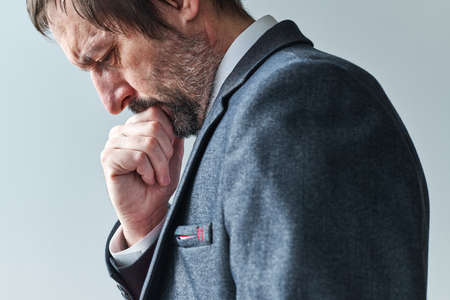 Tired pensive businessman overburdened with thoughts contemplating with hand on chin, selective focus portraitの写真素材