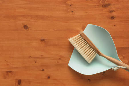 Dustpan and brush on wooden hardwood floor, flat lay top view with copy space includedの写真素材