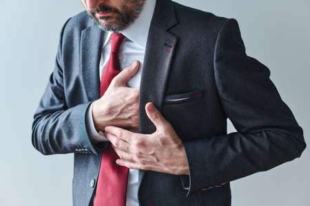 Businessman with cardiovascular problems, adult male entrepreneur having heart-attack, pressing the chest with his handの写真素材