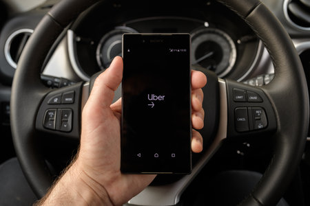 ZRENJANIN, SERBIA - APRIL 2, 2021: Male hand holding smartphone with Uber Driver application screen in the car. Uber is app-based transportation network. Illustrative editorial.のeditorial素材