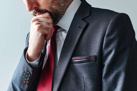 Serious pensive businessman contemplating with hand on chin, selective focus portraitの写真素材
