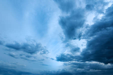 Dramatic stormy cumulus clouds at the sky in spring dusk, cold blue toned image