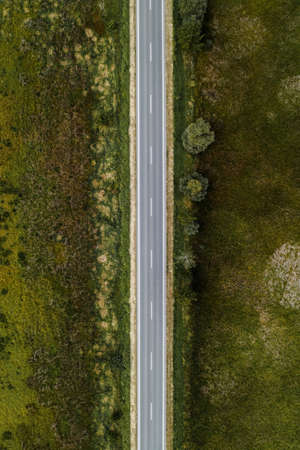 Empty asphalt road through countryside, aerial view from drone pov, Top view roadway as conceptual background for traveling and car insurance themes.の写真素材