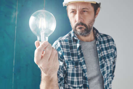 Construction engineer holding light bulb as symbol of creativity and new ideas, selective focusの写真素材