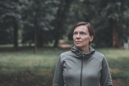 Portrait of adult female jogger in park ready for running on the track, healthy lifestyle and recreational activity in 40sの写真素材