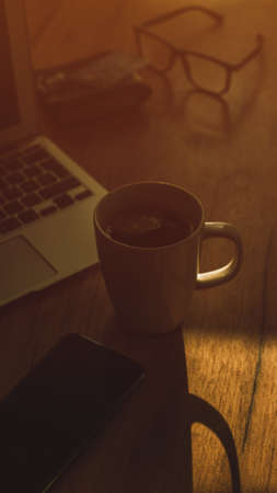 Morning coffee in dark home office interior, low key image with selective focusの写真素材