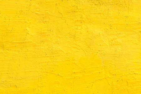 Yellow cement wall as background, unique urban surface texture with vibrant colorの写真素材
