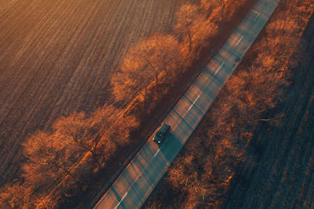 Car driving down the road in sunset, aerial view from drone pov, beautiful countryside landscapeの写真素材