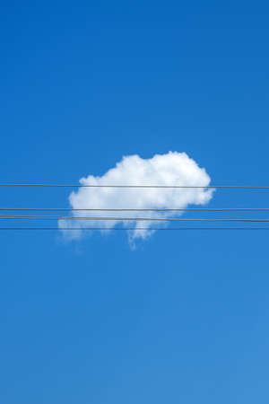 White cloud and electricity wires against blue sky, minimal abstract compositionの写真素材