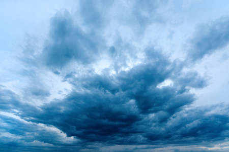 Dramatic stormy cumulus clouds at the sky in spring dusk, cold blue toned imageの写真素材