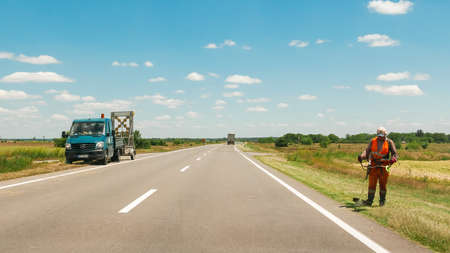 Zabalj, Serbia, June 15. 2020: Workers trimming grass by the road from Zabalj to Zreanjanin in Serbian province Vojvodinaの写真素材