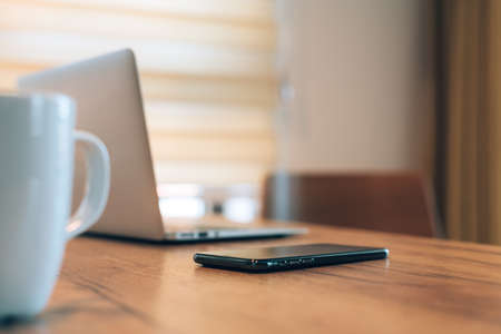 Mobile smart phone, laptop computer and coffee cup at home office workspace, selective focusの写真素材