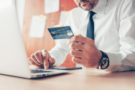 E-business, businessman using credit card and laptop computer for online financial transaction, close up with selective focusの写真素材