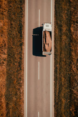 Aerial shot of freight truck transporting sand as construction material, top down drone pov from high angle viewの写真素材
