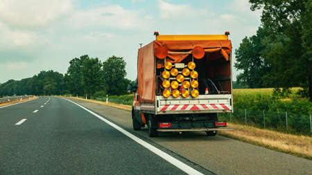 Road maintenance truck and signalization for road works, workers repairing highwayの写真素材