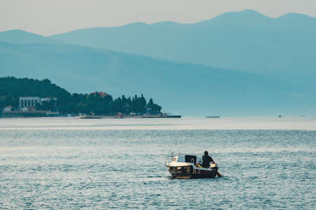 Fisherman and fishing boat in Adriatic sea in early morning, town of Crikvenica in Kvarner bayの写真素材