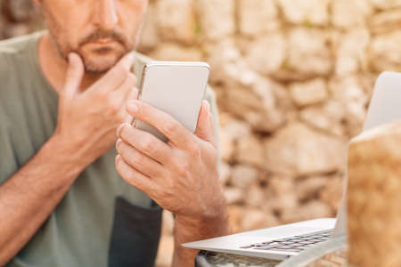 Freelancer and digital nomad working on smartphone and laptop computer during summer vacation...