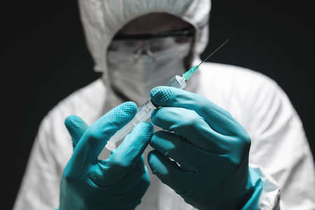 Covid-19 vaccination concept, medical professional holding vaccine injection syringe, closeup with selective focusの写真素材