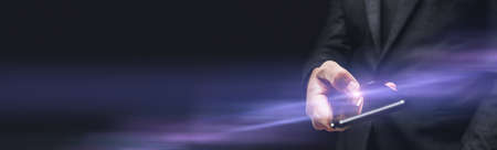 Elegant businessman in dark gray suit using smartphone, panoramic image with copy space and selective focusの写真素材