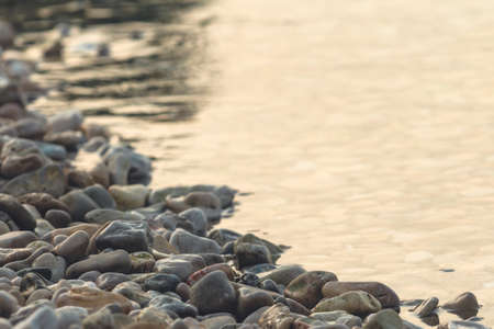 Beach pebbles and sea water in sunrise, summer vacation at seasideの写真素材