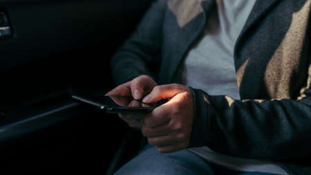 Businesswoman typing text message in car, close up of hands with selective focusの写真素材