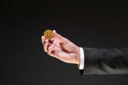 Bitcoin cryptocurrency trader offering a golden coin, selective focusの写真素材