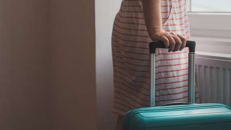 Female tourist pulling travel luggage suitcase into apartment room, selective focusの写真素材
