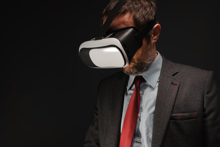 Businessman wearing VR headset goggles in dark office interior, low key portrait with selective focusの写真素材