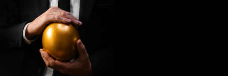 Golden egg in hands of elegant businessman as symbol of guaranteed success, profit or wealth.,...