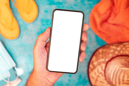 Hand holding mobile smart phone with blank mockup screen at seaside beach, selective focusの写真素材