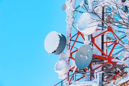Communication tower antennas covered in snow with blue sky as copy spaceの写真素材