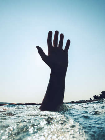 Hand of a drowning man reaching out from the deep cold sea water and asking for help and salvation, selective focusの写真素材